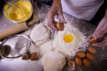 Sezione centrale dello chef che rompe l'uovo sulla farina — Foto stock