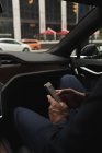 Средняя секция бизнесмена, использующего мобильный телефон в автомобиле — стоковое фото