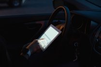 Partie médiane de la femme utilisant la tablette numérique tout en étant assis dans la voiture — Photo de stock