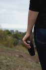 Seção média de mulher segurando uma câmera em uma colina — Fotografia de Stock
