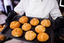 Mid section of chef holding kaiser roll on a tray — Stock Photo