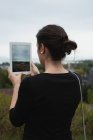 Visão traseira da mulher clicando fotos com tablet digital — Fotografia de Stock