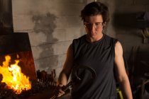 Junge Metallschmiedin hält Hufeisen in Fabrik — Stockfoto