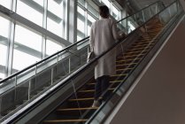 Visão traseira da mulher se movendo na escada rolante na estação ferroviária — Fotografia de Stock