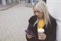 Женщина пользуется мобильным телефоном во время кофе — стоковое фото