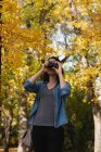 Жінка натискає фотографії з камерою в сонячний день — стокове фото