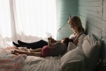 Mutter und Tochter nutzen Handy im Schlafzimmer zu Hause — Stockfoto