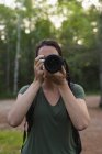 Крупним планом жінка натискає фотографії з камерою в лісі — стокове фото