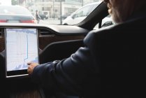 Sección media del hombre de negocios que utiliza el mapa del navegador mientras conduce un coche - foto de stock