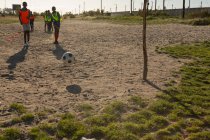 Дети играют в футбол на земле в солнечный день — стоковое фото