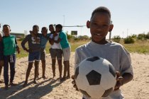 Мальчик держит футбол в земле в солнечный день — стоковое фото