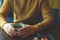 Seção média do homem segurando xícara de café no café — Fotografia de Stock