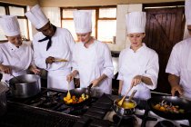 Gruppe von Köchen bereitet Essen in der Küche zu — Stockfoto
