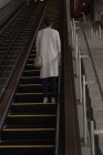 Rear view of woman moving up on escalator at railway station — Stock Photo