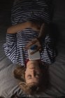Mujer usando teléfono móvil en la cama en el dormitorio en casa - foto de stock