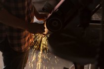 Female metalsmith using sharpening machine in factory — Stock Photo