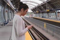 Жінка використовує мобільний телефон на платформі на залізничному вокзалі — стокове фото