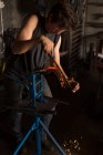 Fer à cheval de mise en forme de forgeron féminin attentif dans l'usine — Photo de stock