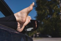 Baixa seção de mulher relaxante com os pés para cima em um carro — Fotografia de Stock