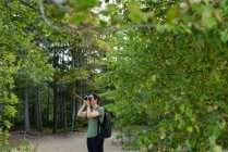 Frau klickt mit Kamera auf Fotos im Wald — Stockfoto