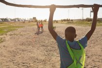 Rear view of boy hanging on goal post in the ground — Stock Photo