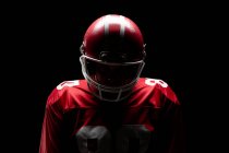 American football player standing with rugby helmet against black background — Stock Photo