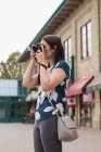 Женщина выкладывает фотографии с камеры в городе — стоковое фото
