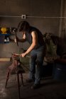 Attentive female metalsmith molding horseshoe in factory — Stock Photo