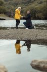 Young man proposing to woman near river — Stock Photo