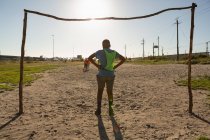 Rear view of boy standing on goal post in the ground — Stock Photo