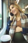 Primer plano de la mujer embarazada hablando por teléfono móvil mientras viaja en tren - foto de stock