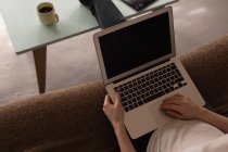 Средняя секция женщины, использующей ноутбук дома — стоковое фото