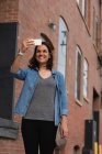 Frau klickt an einem sonnigen Tag mit Handy in der Stadt auf Fotos — Stockfoto