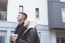 Улыбающаяся пара смотрит в сторону, когда пьет кофе — стоковое фото