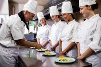 Chefe de cozinha inspecionando pratos de sobremesa no restaurante — Fotografia de Stock