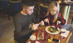 Jeune couple ayant de la nourriture au restaurant — Photo de stock