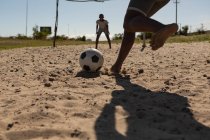 Enfants jouant au football dans le sol par une journée ensoleillée — Photo de stock