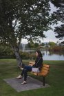 Thoughtful woman sitting on bench near riverside — Stock Photo
