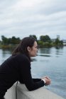 Вдумлива жінка, що стоїть біля берега річки — стокове фото