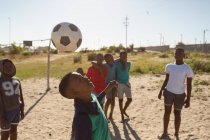 Хлопчик грає у футбол на землі в сонячний день — стокове фото