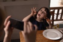 Мати натискає фотографію дочки, коли їсть вдома — стокове фото