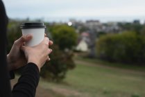 Partie médiane de la femme tenant une tasse de café sur une colline — Photo de stock