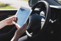 Gros plan de la femme utilisant une tablette numérique dans une voiture — Photo de stock