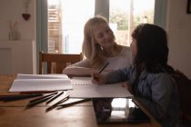 Mother helping her daughter with homework at home — Stock Photo