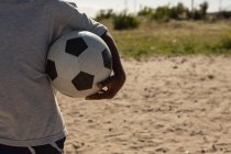 Mittelteil des Jungen hält Fußball in der Luft — Stockfoto
