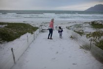 Madre e hija divirtiéndose en la playa durante el invierno - foto de stock