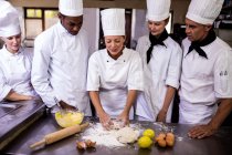Cuoca che insegna al suo team a preparare l'impasto in cucina — Foto stock