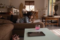 Menina lendo um livro na sala de estar em casa — Fotografia de Stock