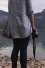 Середина жінки, що виступає з камерою біля берега озера — стокове фото