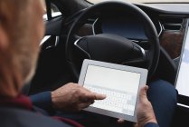 Средняя секция бизнесмена, использующего цифровой планшет в автомобиле — стоковое фото